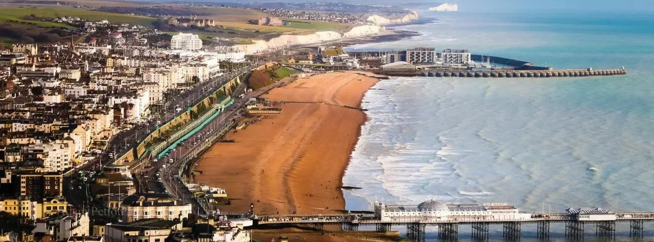 Vue aérienne d'une côte avec une plage de sable, des bâtiments et un quai en bois